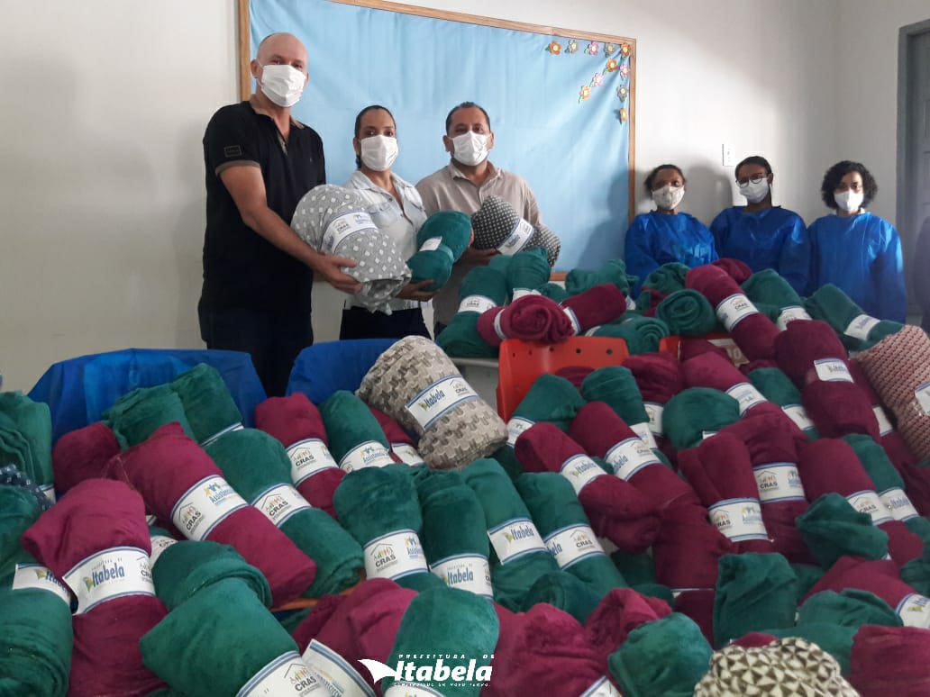 Autoridades e equipe durante entrega de cobertores às famílias